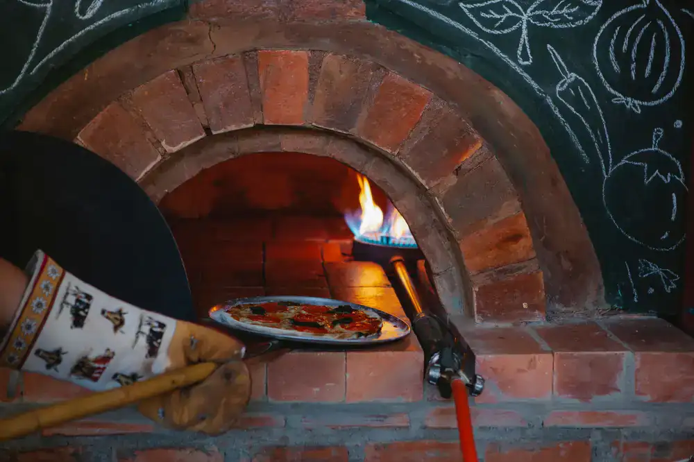 Fresh pizza baking in a wood-fired oven inside the van