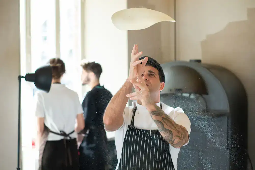 Chef tossing fresh pizza dough outside the mobile van